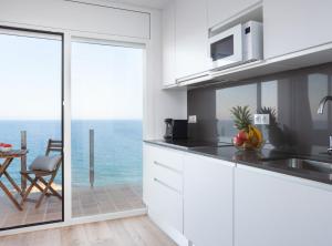 a kitchen with white cabinets and a view of the ocean at La Cala Beach Deluxe Apartments in L'Ametlla de Mar +11 photos