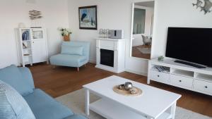 ein Wohnzimmer mit einem Sofa, einem TV und einem Tisch in der Unterkunft Loft 5 - Urlaub direkt an der Förde in Flensburg