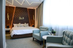 a hotel room with a bed and two chairs at Hotel Pupin Novi Sad in Novi Sad +47 photos