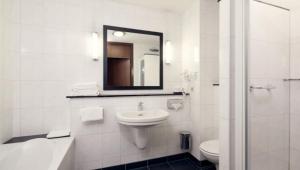 a bathroom with a toilet, sink and mirror at Van der Valk Hotel Eindhoven in Eindhoven