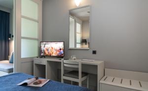 a bedroom with a desk with a tv and a bed at Aeolos Beach Resort in Gastouri