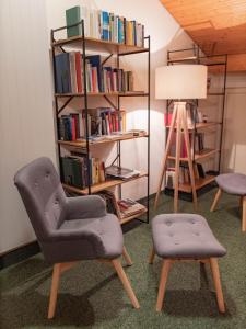 a room with two chairs and a book shelf with books at Silserhof - ankommen, auftanken, aufatmen in Sils Maria