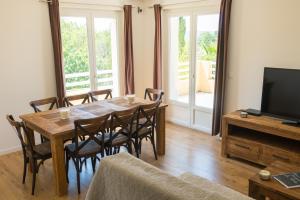 a dining room with a table and chairs and a television at Villa Vaunage Piscine Chauffée in Langlade
