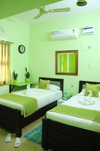 a bedroom with two beds and a clock on the wall at Hotel NKC Airport in Chennai