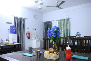 a dining room table with a vase of blue flowers at Hotel NKC Airport in Chennai
