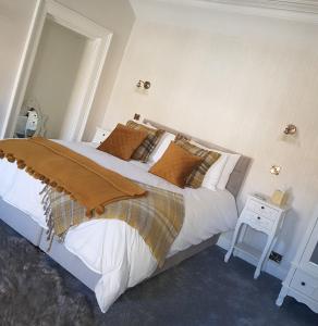 um quarto com uma grande cama branca e uma mesa em The Covenanter Hotel em Falkland