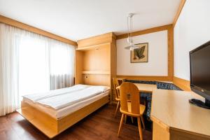 una camera con letto e scrivania con computer di Residence Contrin a Canazei