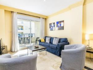 sala de estar con sofá azul y sillas en Apartamento 357, en Marbella