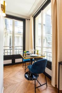 ein Esszimmer mit einem Tisch und Stühlen sowie einem großen Fenster in der Unterkunft CMG Champs Elysees - Boetie 5 in Paris