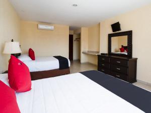 una camera d'albergo con due letti e uno specchio di Capital O Hotel Los Caracoles, Acapulco ad Acapulco
