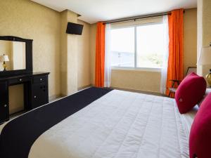 - une chambre avec un grand lit et une grande fenêtre dans l'établissement Capital O Hotel Los Caracoles, Acapulco, à Acapulco
