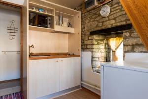a kitchen with white cabinets and a stone wall at The Folly in Tetbury