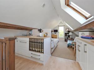 uma cozinha com armários brancos e uma cama num sótão em Shrove em Chedworth