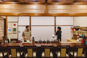 un hombre y una mujer de pie en una cocina en Couch Potato Hostel, en Matsumoto