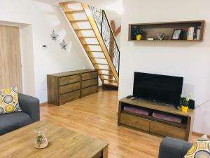 a living room with a television and a staircase at Apartmány Rychtaříkovi in Černý Dŭl