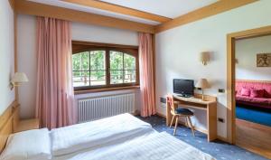 a bedroom with a bed and a desk with a computer at Garni Aritz in Campitello di Fassa +37 photos