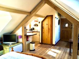an attic room with a bed and a television at Greencourt Loft - The Cotswold Way, Stroud in Stonehouse