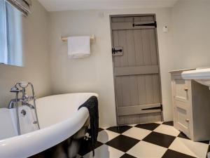 a bathroom with a tub and a checkered floor at Cosy Cot in Stoford
