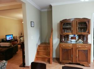 a living room with a wooden cabinet and a staircase at Avó Lucindinha House - Porto Moniz in Porto Moniz