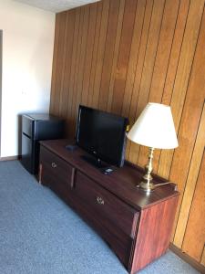 a room with a television on a dresser with a lamp at Harcourt Motel in Mount Vernon