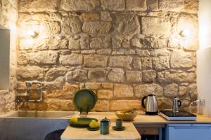 a kitchen with a stone wall and a table with bananas at IL CORVO DI PIETRA in Scicli