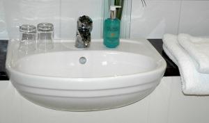 a white sink with a bottle of soap and towels at The Long Range in Budleigh Salterton