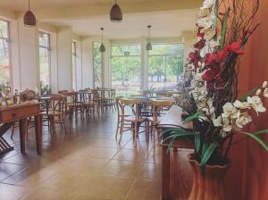 um restaurante com mesas e cadeiras e flores numa sala em Pousada Pontal do Lago em Carmo do Rio Claro