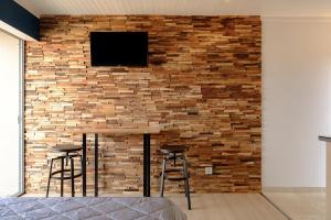 Una pared de ladrillo con dos taburetes y una TV. en Studio climatisé île naturiste du Levant en Hyères