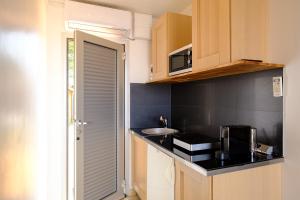 a small kitchen with a sink and a microwave at Studio climatisé île naturiste du Levant in Hyères