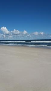 a sandy beach with the ocean in the background at Pokoje Goscinne Bemar in Jastarnia