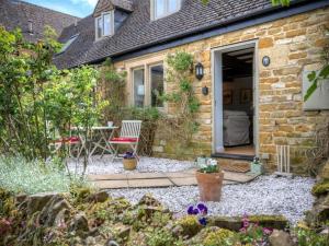 un cottage in pietra dotato di patio con tavolo e sedie. di Bobble Cottage a Bourton on the Water