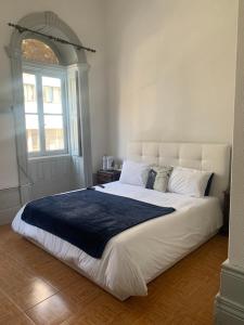 a white bed sitting in a bedroom next to a window at Residência Céu Azul in Porto