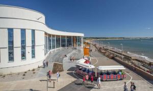 un grupo de personas de pie fuera de un edificio al lado de un muelle en Kittiwake Number 4 - Town Centre & Spacious, en Bridlington