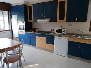 Eine Küche mit blauen Schränken, einem Tisch und einer Spüle in der Unterkunft Casa Ribe in Tui