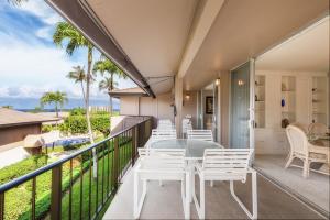 Un balcón con sillas blancas y una mesa. en Maui Eldorado D200 - 2 Bedroom, en Lahaina