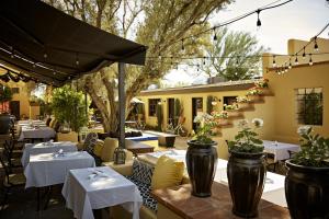 un restaurante con mesas blancas, sillas y árboles en Bespoke Inn Scottsdale, en Scottsdale