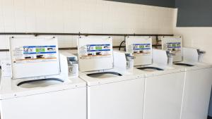 a row of white washing machines in a room at Motel 8 Laramie in Laramie