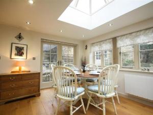 a dining room with a table and chairs and a skylight at Coach House Burford in Burford