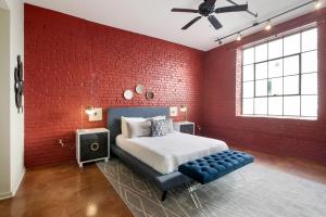 a red brick bedroom with a bed and a blue ottoman at LiivUP Warehouse Apartments in New Orleans