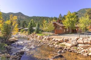 einem Fluss vor einem Blockhaus in der Unterkunft Woodlands on Fall River in Estes Park