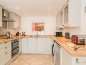 une cuisine avec des armoires blanches et un comptoir dans l'établissement Swallows Cottage, à Harley