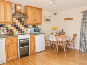a kitchen with wooden cabinets and a table with a microwave at Ash Cottage in Llandysul