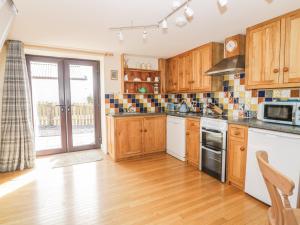 a kitchen with wooden cabinets and a stove top oven at Ash Cottage in Llandysul