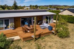 a house with a wooden deck with a table and chairs at Fern Haven in Martinborough