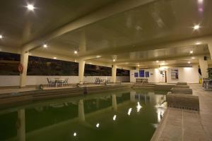 a pool of water in a building with tables and chairs at D'Acosta Hotel Sochagota in Paipa