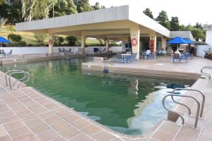 une piscine d'eau avec des chaises et des tables dans un bâtiment dans l'établissement D'Acosta Hotel Sochagota, à Paipa