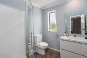 a white bathroom with a toilet and a sink at Fern Haven in Martinborough  +19 photos