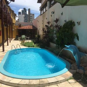 a swimming pool with a dolphin water fountain at Pousada Coco Verde Natal in Natal