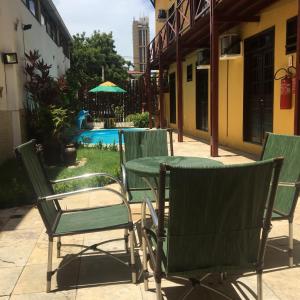 un patio con mesa, sillas y piscina en Pousada Coco Verde Natal, en Natal