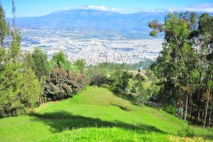 a green hill with a view of a city at La Estelita in Ibarra